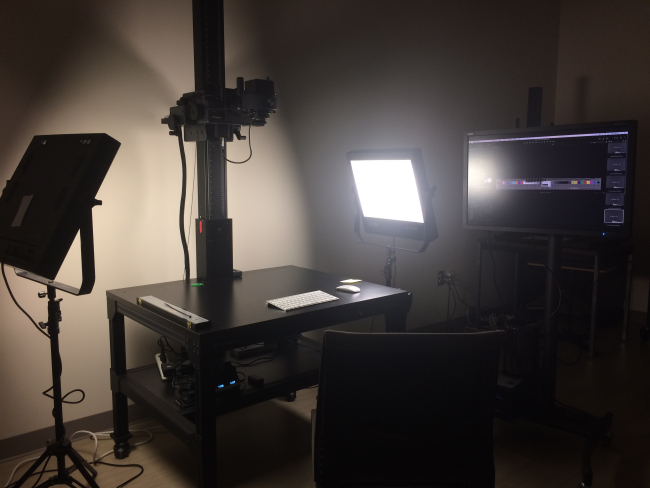 Large flat bed table with camera positioned above it and two industry standard lights on either side of the table.