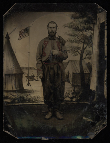 Civil War solider stands at attention in military encampment 