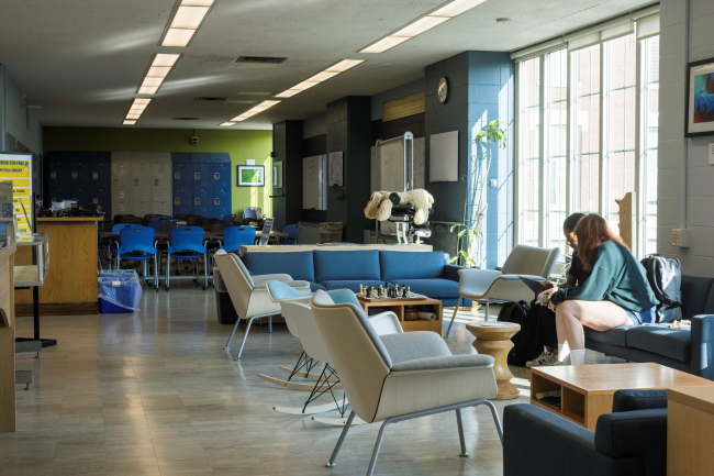 A view of POA's lounge area from where the stacks begin. Two students are sharing one of the couches