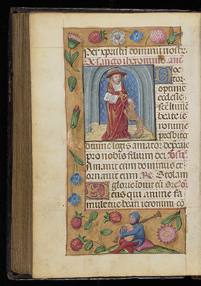 A page from an illuminated manuscript featuring a central illustration of Saint Jerome dressed in red robes, holding a book and accompanied by a lion. The scene is set within a blue and gray architectural arch. To the right of the illustration is a column of Latin text in blackletter script with an ornate gold initial. The page is richly decorated with a floral border of pink, red, and blue flowers, green leaves, and a small figure at the bottom picking flowers. The manuscript is slightly open, showing the