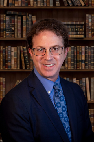Photo of a man, Mark Zaid, in front of a bookshelf
