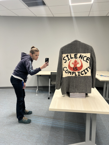 Lisa Wright using a phone to take photos of Col Raimond's jacket for photogrammetry. 