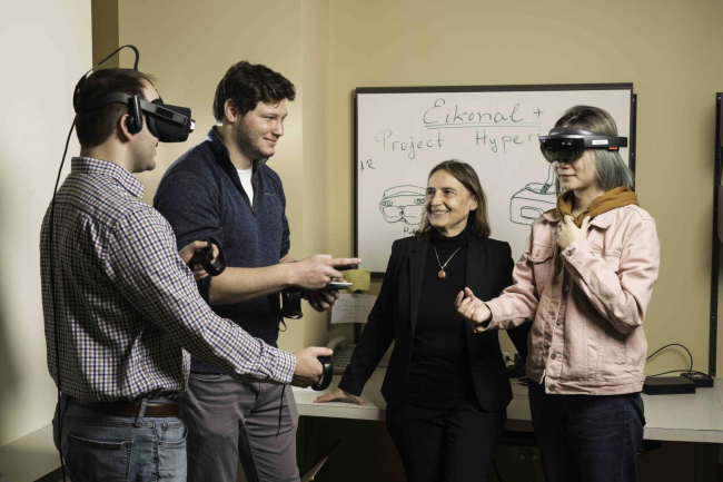 Jannick Rolland smiling with folks in XR headsets. 