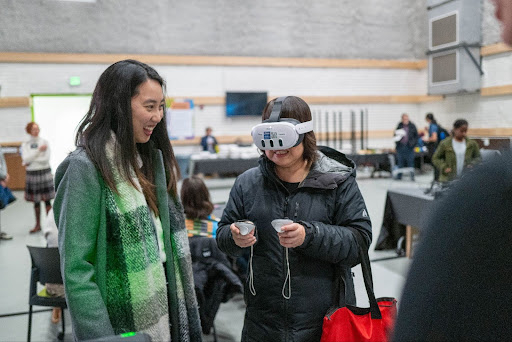 Person trying virtual reality with an onlooker.
