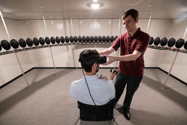 Biomedical engineering graduate student Tom Stoll, right, adjusts a virtual reality head-mounted display on assistant professor Ross Maddox. The array of speakers in Maddox's lab allows researchers to simulate realistic listening environments.	Biomedical engineering graduate student Tom Stoll, right, adjusts a virtual reality head-mounted display on assistant professor Ross Maddox. The array of speakers in Maddox's lab allows researchers to simulate realistic listening environments. (University photo / J. A